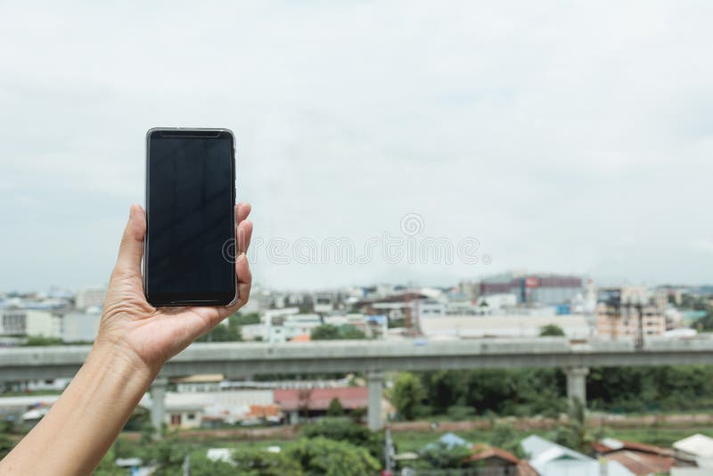 Smart telefon för kvinnahandinnehav med byggnadsbakgrund royaltyfri foto Smart telefon för kvinnahandinnehav med byggnadsbakgrund royaltyfri foto