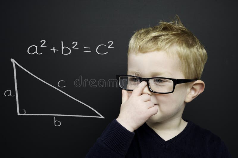 Smart young boy stood infront of a blackboard stock photos