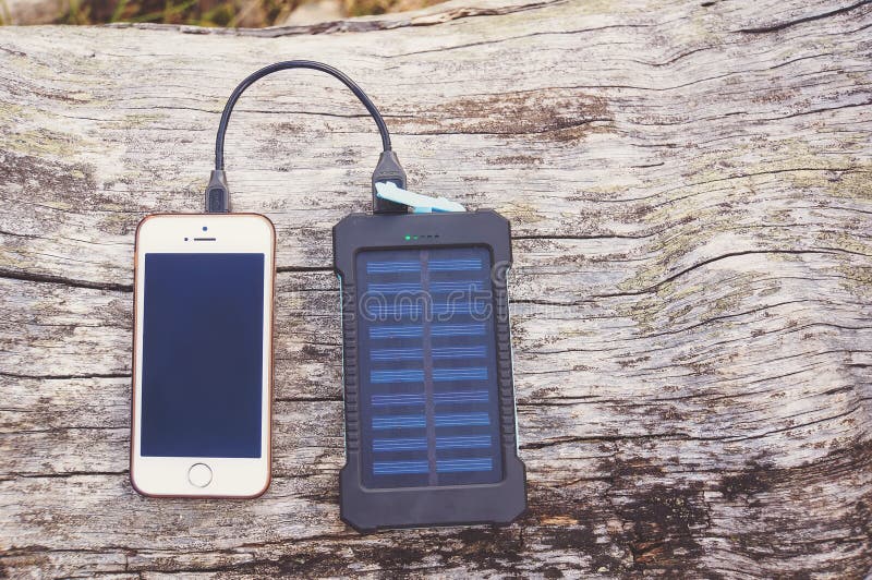 Smartphone charging with pink power bank on wood background stock image Smartphone charging with pink power bank on wood background stock image