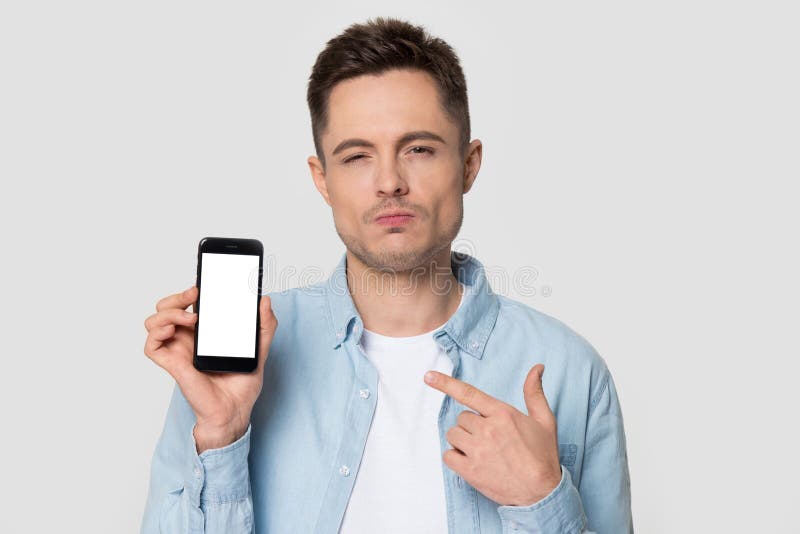Smartphone confuso di manifestazione dell'uomo del ritratto di colpo in testa con lo schermo bianco del modello fotografia stock Smartphone confuso di manifestazione dell'uomo del ritratto di colpo in testa con lo schermo bianco del modello fotografia stock