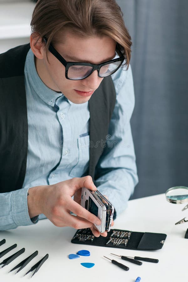 Smartphone de démontage d'homme dans l'atelier de réparations image stock Smartphone de démontage d'homme dans l'atelier de réparations image stock