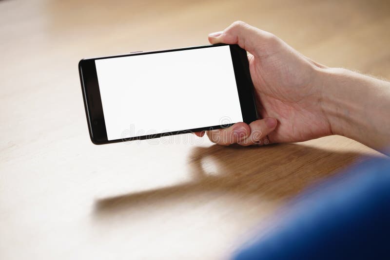 Smartphone della tenuta della mano del giovane con lo schermo bianco in bianco immagine stock libera da diritti Smartphone della tenuta della mano del giovane con lo schermo bianco in bianco immagine stock libera da diritti