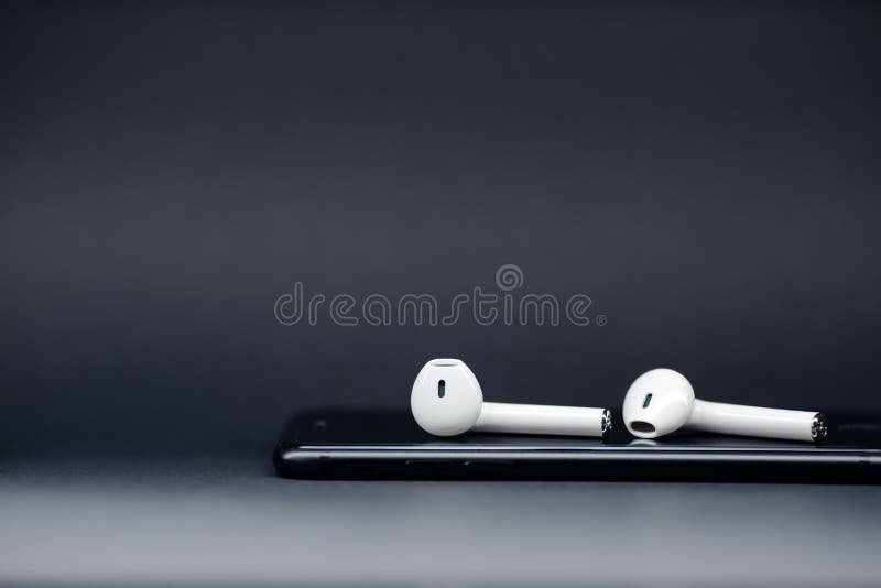 Smartphone e cuffie wireless isolati sullo sfondo grigio immagini stock libere da diritti