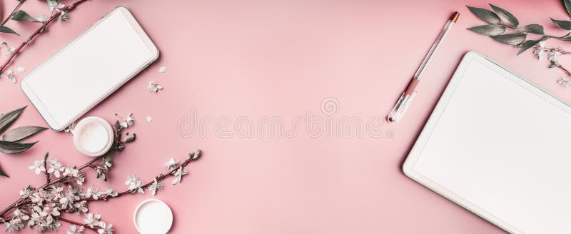 Smartphone et moquerie de PC de comprimé sur le fond de bureau rose en pastel avec du cosmétique, les supples de papeterie et les