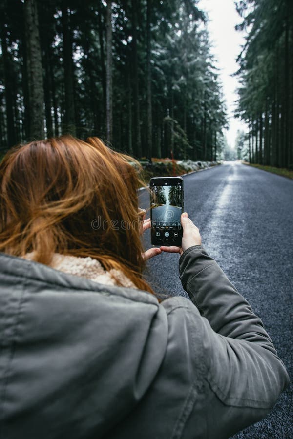 Smartphone in hand on the background winter road in the woods royalty free stock photos Smartphone in hand on the background winter road in the woods royalty free stock photos