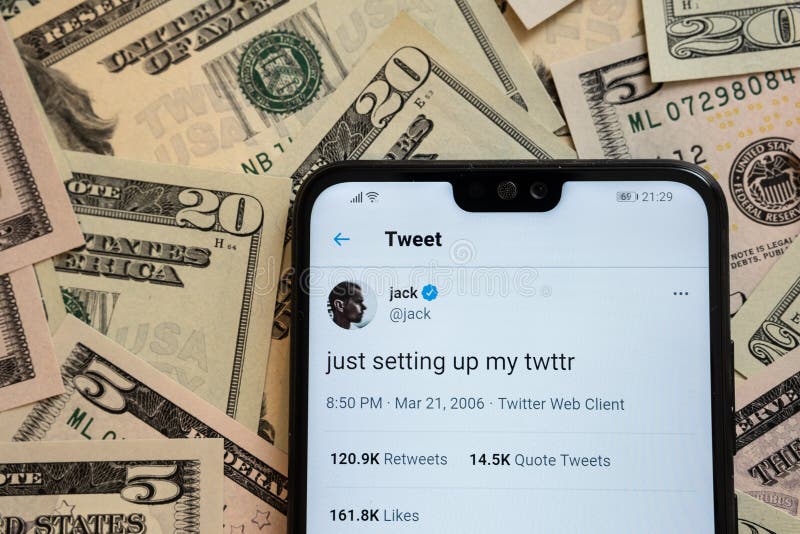 Smartphone with Jack Dorseys tweet `just setting up my twttr` placed on dollar bills.  First ever tweet sold as a non fungible tok