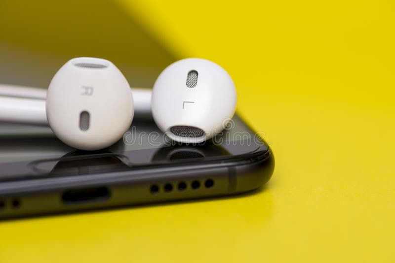 Smartphone med hörlurar på färgbakgrund Närbild av den smarta telefonen med hörlurar på en gul bakgrund lyssnar musik till arkivbilder Smartphone med hörlurar på färgbakgrund Närbild av den smarta telefonen med hörlurar på en gul bakgrund lyssnar musik till arkivbilder