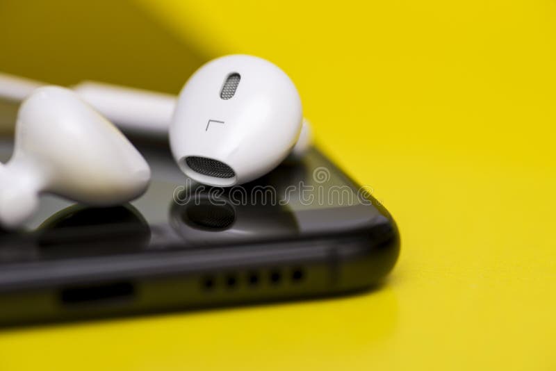 Smartphone met oortelefoons op kleurenachtergrond Smartphone en oortelefoon op gele achtergrond Close-up van smartphone met royalty-vrije stock afbeeldingen Smartphone met oortelefoons op kleurenachtergrond Smartphone en oortelefoon op gele achtergrond Close-up van smartphone met royalty-vrije stock afbeeldingen