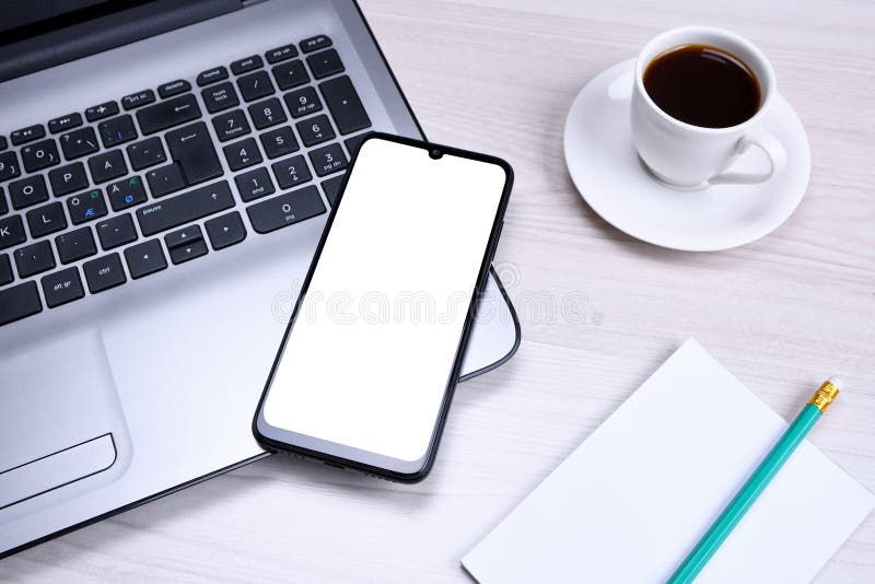 Smartphone, Mobile Phone with White Screen on a Gray Laptop on the Desktop. Mock Up Stock Photo