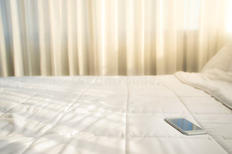 The Smartphone is Placed on a Bed with a White Sheet Stock Image