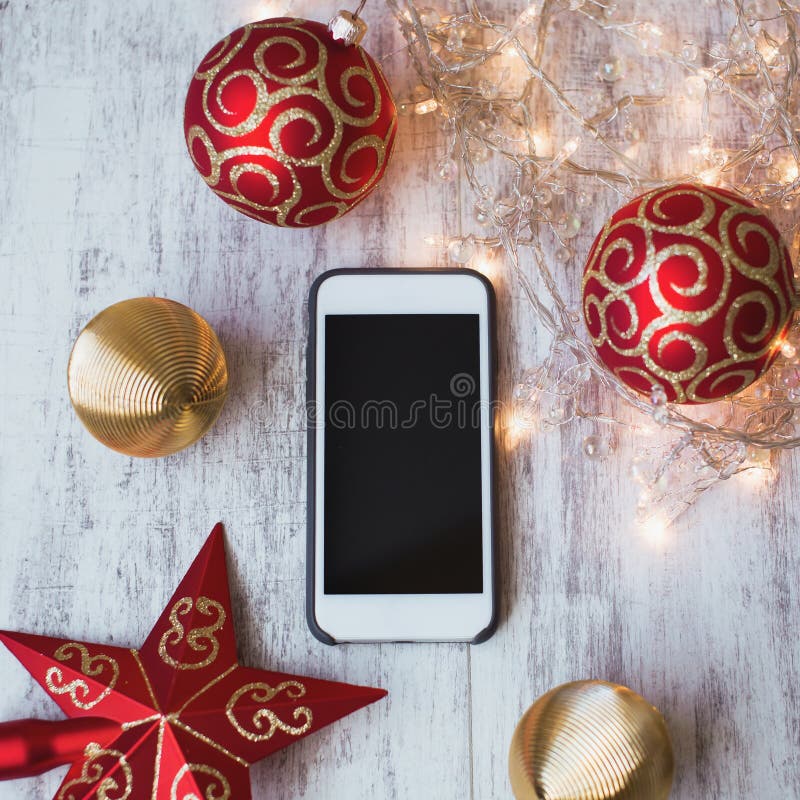 Smartphone på en vit träbakgrund med julleksaker och ljus arkivfoto Smartphone på en vit träbakgrund med julleksaker och ljus arkivfoto