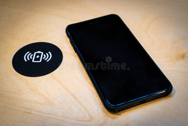 Smartphone que carrega em uma tabela com uma almofada de carregamento sem fio imagens de stock royalty free Smartphone que carrega em uma tabela com uma almofada de carregamento sem fio imagens de stock royalty free