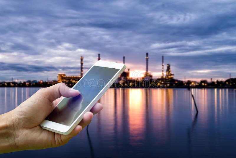 Smartphone van de handholding op vage de industrieinstallatie a van de Olieraffinaderij stock foto's Smartphone van de handholding op vage de industrieinstallatie a van de Olieraffinaderij stock foto's