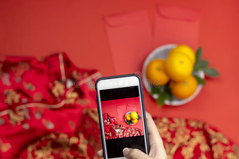 Smartphone van de de handholding van de vrouw vangt Chinese nieuwe van angpaozak en qipao van jaarsinaasappelen kleding stock foto's Smartphone van de de handholding van de vrouw vangt Chinese nieuwe van angpaozak en qipao van jaarsinaasappelen kleding stock foto's