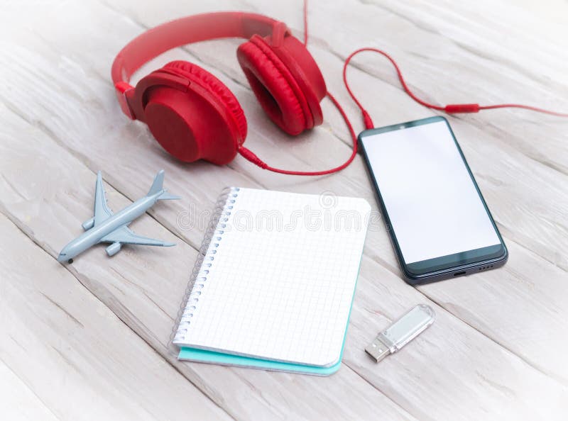 Smartphone with a white display, with headphones and an airplane model. On-ear headphones with a memory card, with a notepad with royalty free stock photo