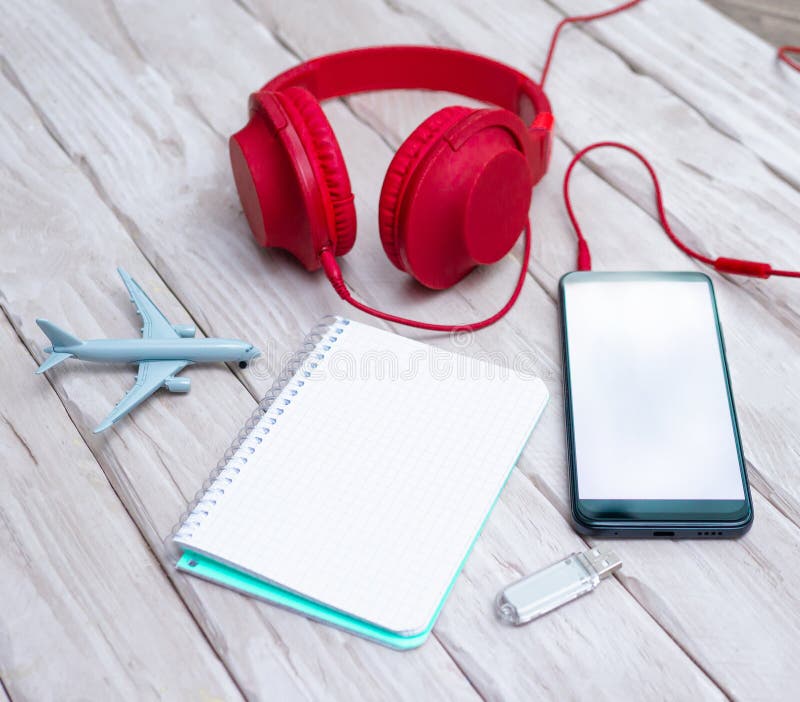 Smartphone with a white display, with headphones and an airplane model. Overhead headphones with a notepad with a blank message royalty free stock images