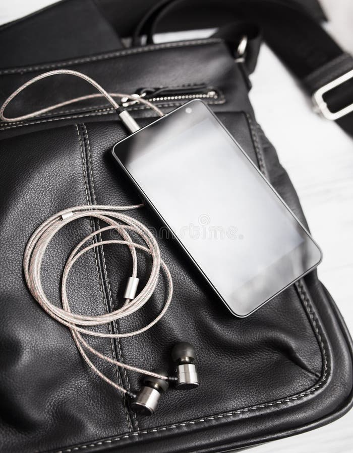 Smartphone z słuchawkami na czarnej skórze zdjęcia stock Smartphone z słuchawkami na czarnej skórze zdjęcia stock