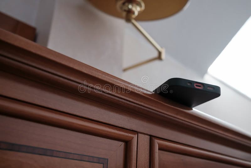 Smartphone är skoningslöst placerad på kanten av dressern och kan falla. Begreppet vårdslös attityd till saker och ting. nederst royaltyfri bild