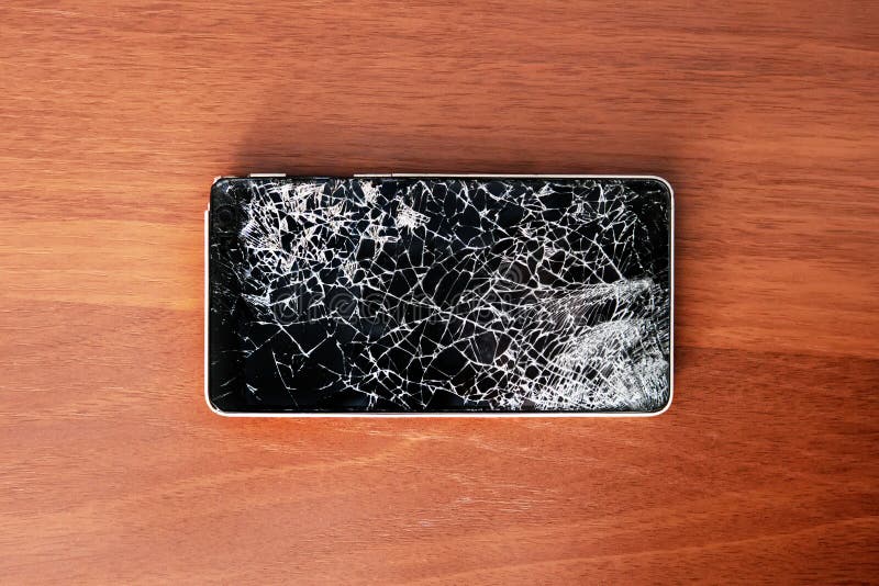 Smartphone с сломленным экраном на деревянном столе стоковое фото rf Smartphone с сломленным экраном на деревянном столе стоковое фото rf