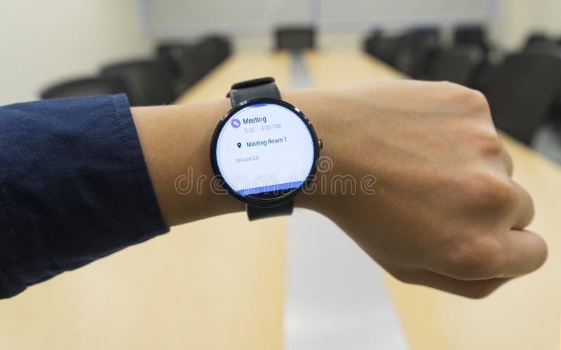 Smartwatch di sguardo dell'uomo di affari a programma di ordine del giorno di manifestazione della sala riunioni quando dove ed o fotografia stock Smartwatch di sguardo dell'uomo di affari a programma di ordine del giorno di manifestazione della sala riunioni quando dove ed o fotografia stock