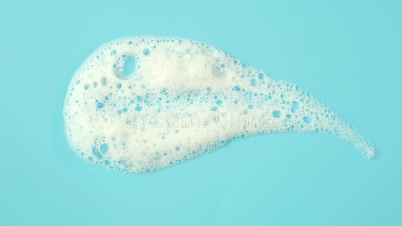 Smear of facial cleansing foam on blue background close-up.