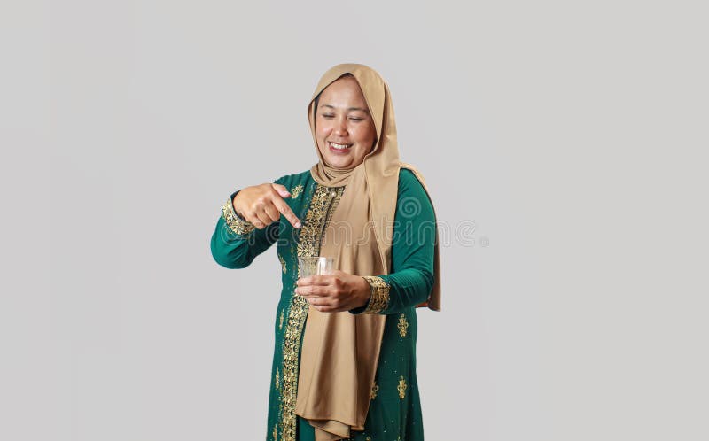 Smilande muslimska kvinnor som pekar på ett glas vatten i traditionell utrustning fotografering för bildbyråer