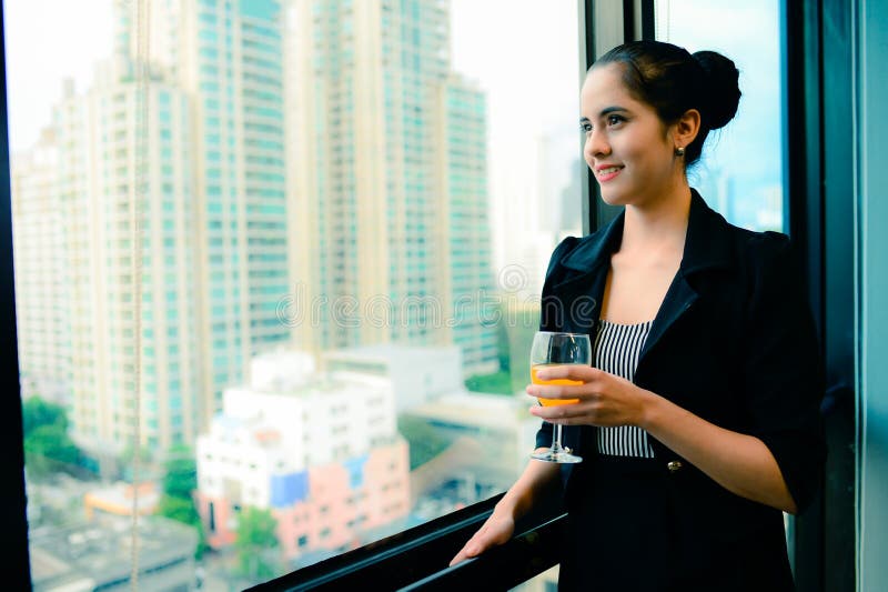 Smile of beautiful business woman at the window with champagne, vintage style
