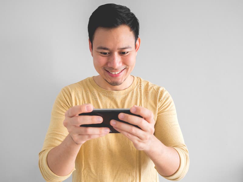 Asian Man Is Playing Mobile Game Seriously. Stock Photo, Picture