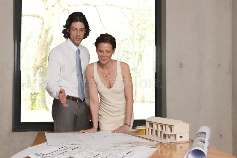 Young man showing his wife the plans for their new home. Young man showing his wife the plans for their new home