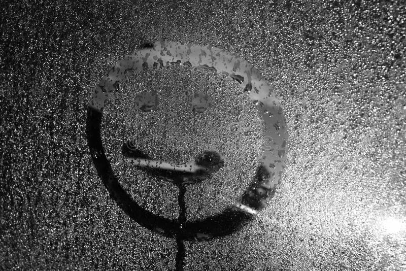 Smiling face freshly painted with a finger of a cars wet window pane. Smiling face freshly painted with a finger of a cars wet window pane