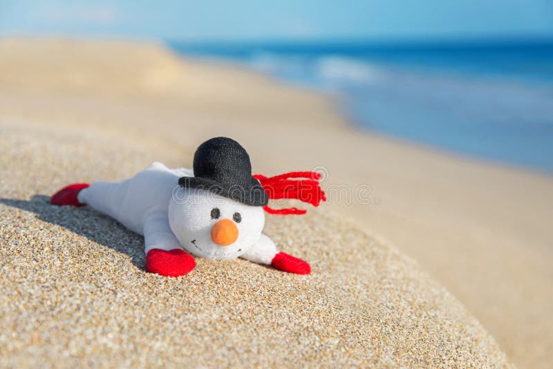 Smiley toy christmas snowman at hot sea beach.