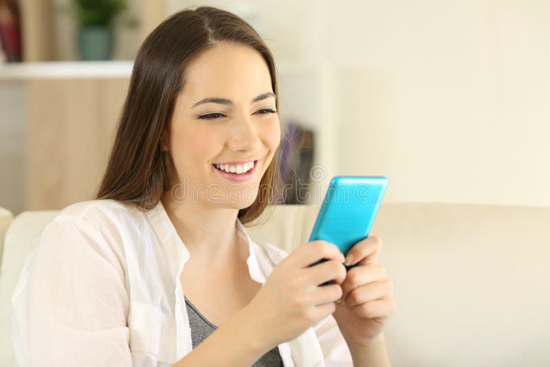 Smileyvrouw die blauwe smartphone op een bank met behulp van royalty-vrije stock foto Smileyvrouw die blauwe smartphone op een bank met behulp van royalty-vrije stock foto