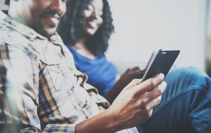 Smiling african american couple relaxing together on the couch.Young black man and his girlfriend using smartphones royalty free stock photos Smiling african american couple relaxing together on the couch.Young black man and his girlfriend using smartphones royalty free stock photos