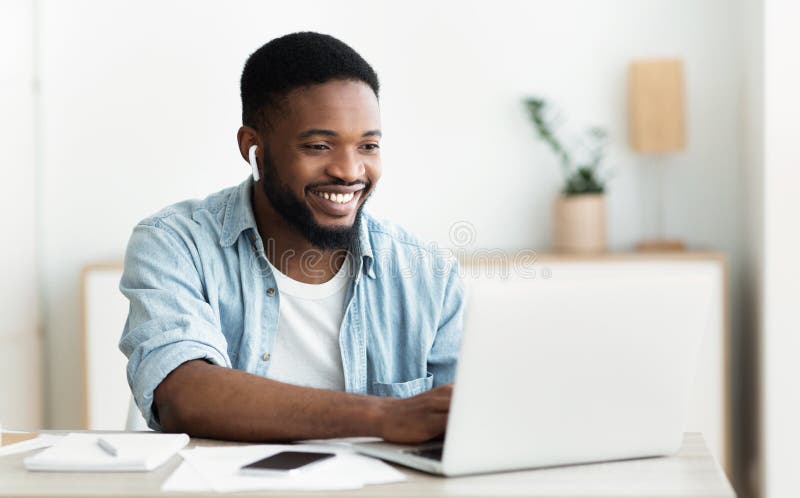 Smiling african-american guy in earphones studying foreign language online royalty free stock photo