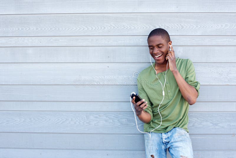 Smiling african american guy listening to music with earphones