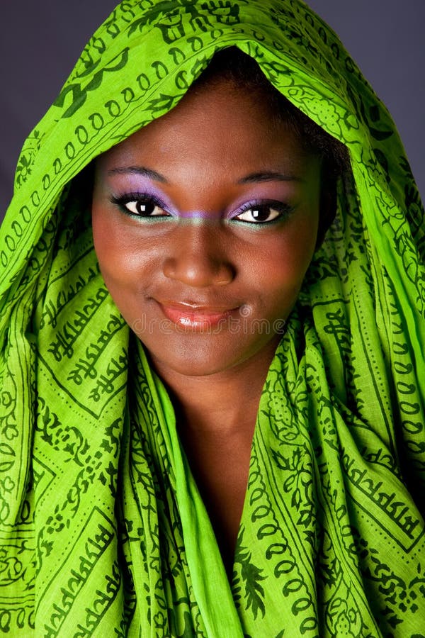 Tvář nevinného usmívající se krásná mladá Africká Americká žena s zelené headwrap a fialová-zelená make-up, izolované.