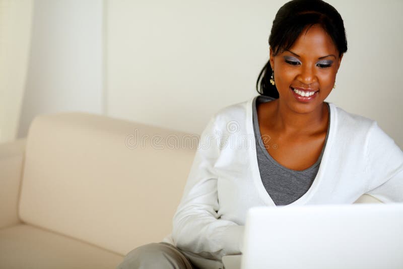 Smiling afro-American woman using laptop stock photography