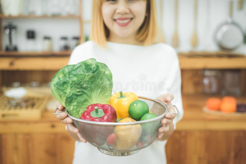 Smiling asian beautiful woman sitting in the kitchen at home and holding a salad bowl. royalty free stock images Smiling asian beautiful woman sitting in the kitchen at home and holding a salad bowl. royalty free stock images