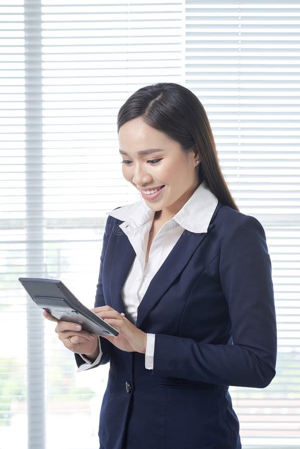 Smiling asian businesswoman in bright office using calculator royalty free stock photo Smiling asian businesswoman in bright office using calculator royalty free stock photo