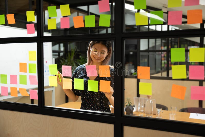Smiling asian female project manager in eyewear organizing working process. royalty free stock photography