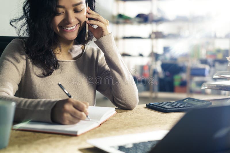 Portrait of a smiling young girl from Asia who is working in an office. She is on the phone with a client and taking notes. Notes office stock images, royalty-free photos and pictures