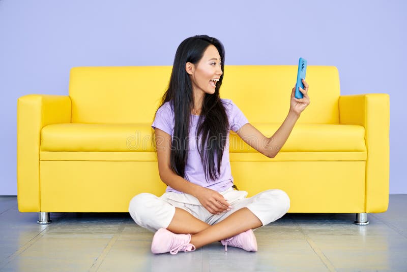 Smiling asian woman making video call by cell phone talking with friends or family