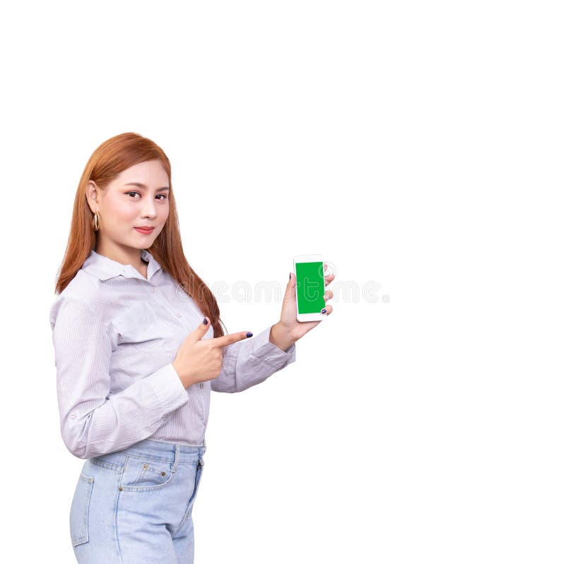 Smiling Asian woman standing in casual shirt holding mobile phone and pointing on smartphone isolated on white background stock image Smiling Asian woman standing in casual shirt holding mobile phone and pointing on smartphone isolated on white background stock image