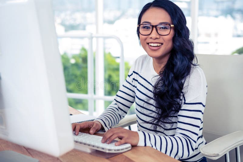 Smiling Asian woman using computer and looking at the camera in office. Computer editing stock images, royalty-free photos and pictures