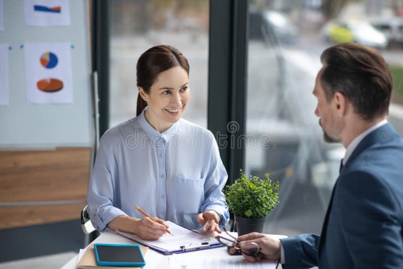 Smiling assistant talking to businessman and making some notes in the morning stock photos