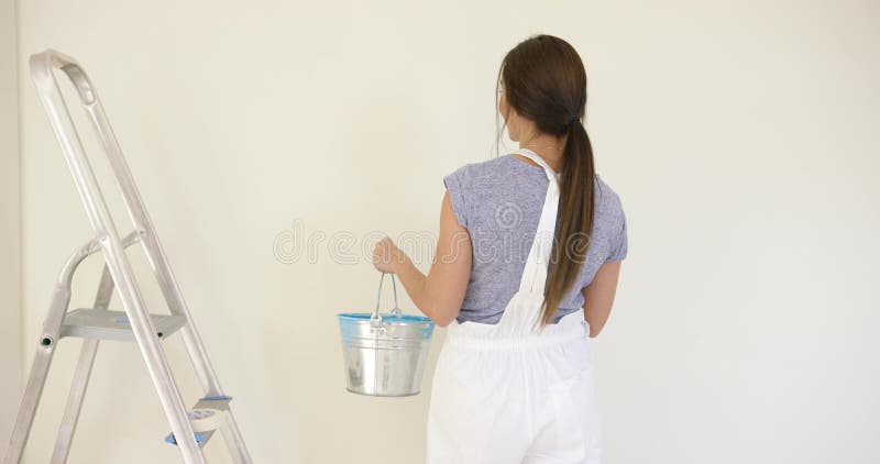 Smiling attractive woman painting her home