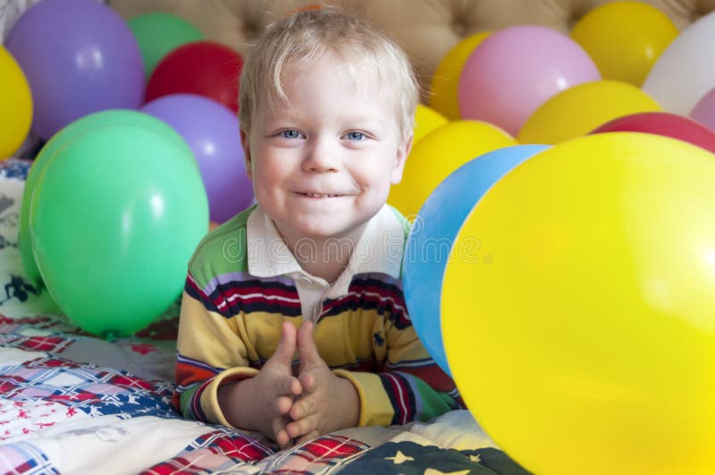 Smiling baby boy with balloons.