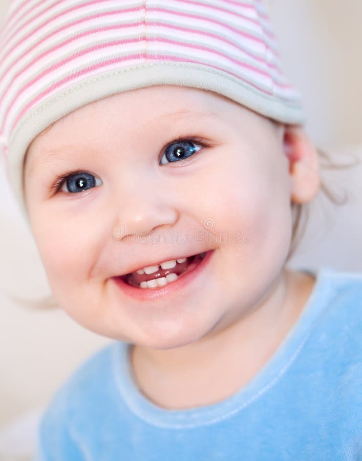 Smiling baby girl showing teeth wearing a hat