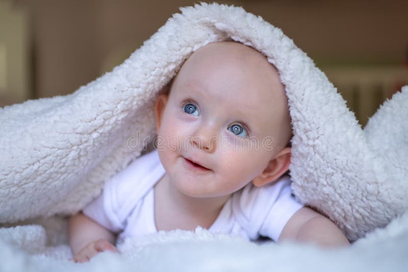 Smiling Baby Looking At Camera Under A White Blanket Towel Stock Photo