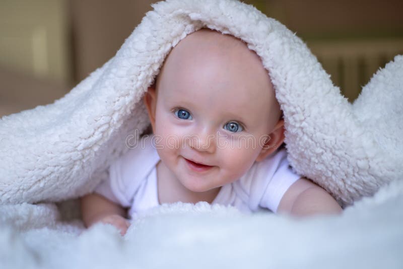 Smiling Baby Looking At Camera Under A White Blanket Towel Stock Photo